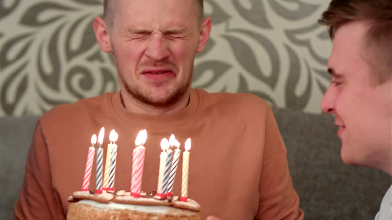 el chico guapo sueña con su deseo y sopla velas en el pastel de cumpleaños y bebe jugo de naranja.