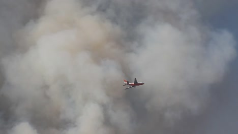 large airplane flying through smoke fighting a california wildfire