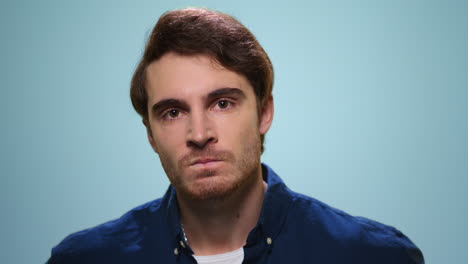 retrato de hombre agresivo en fondo azul. tipo enojado posando ante la cámara en el estudio