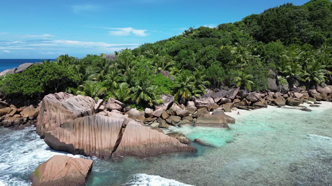 La Digue Island, Seychelles archipelago Indian Ocean drone above white sand beach with waves crashing in to rocks and palm tree jungle paradise vacation vibes