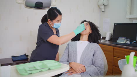 dentist with face mask checking teeth of female