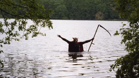 static view of a man with dog head and scythe rising from the waters