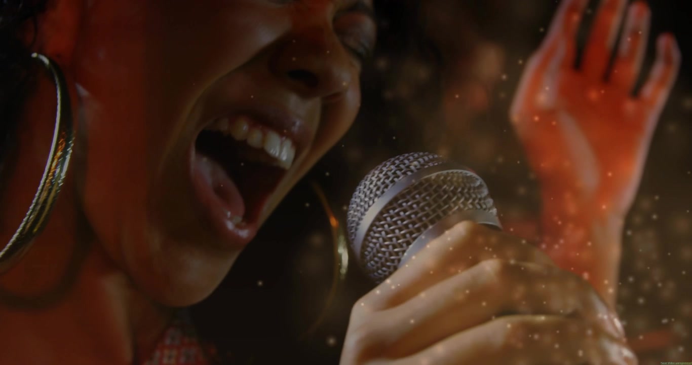 Female singer holding mic close singing loud then soft, engaging music crowd, particles around her