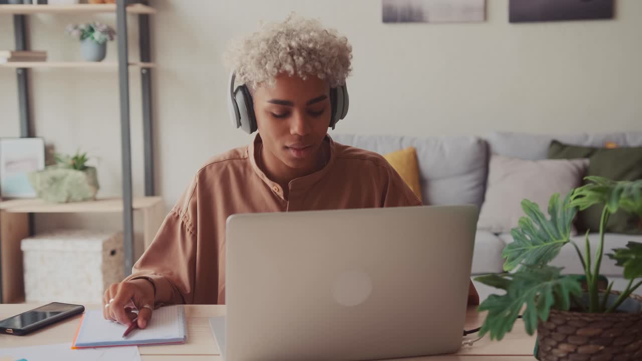 Smiling african woman putting on wireless headphones starting work day remotely
