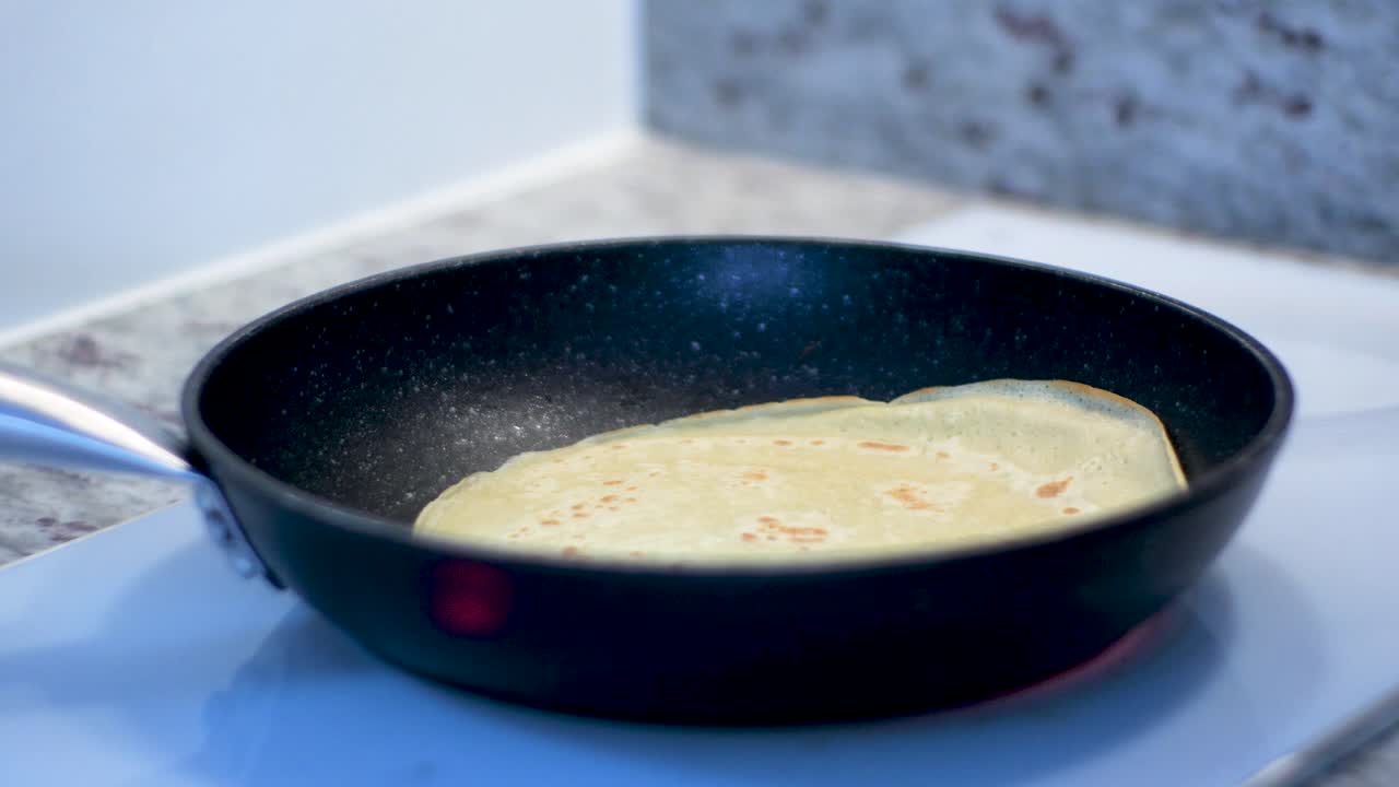 Close up of throwing up pancake in frying pan