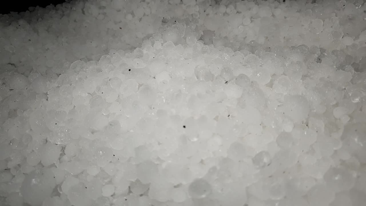 bolas de hielo de tormenta de granizo blanco que se palean y se mueven en una pila para su limpieza y eliminación