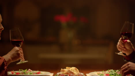 Old-couple-hands-clinking-wine-glasses-during-romantic-dinner