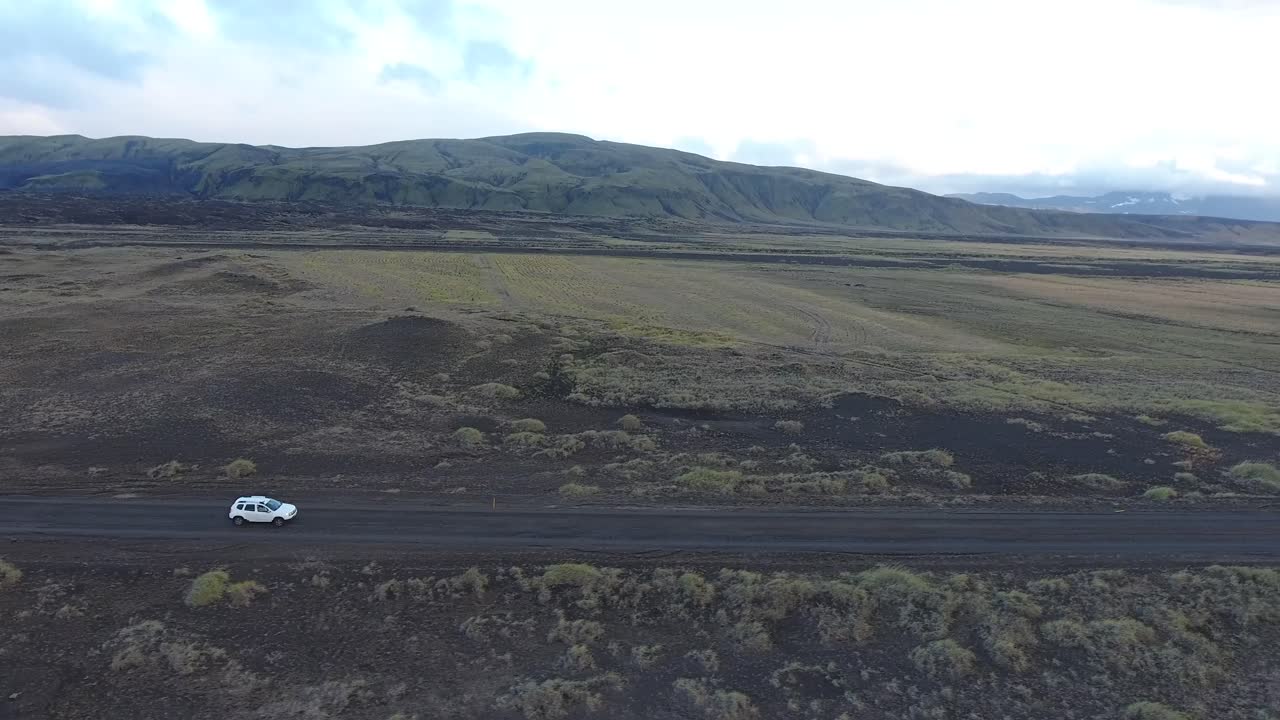 tomada aérea de un avión no tripulado de un coche que conduce fuera de carretera en islandia.
