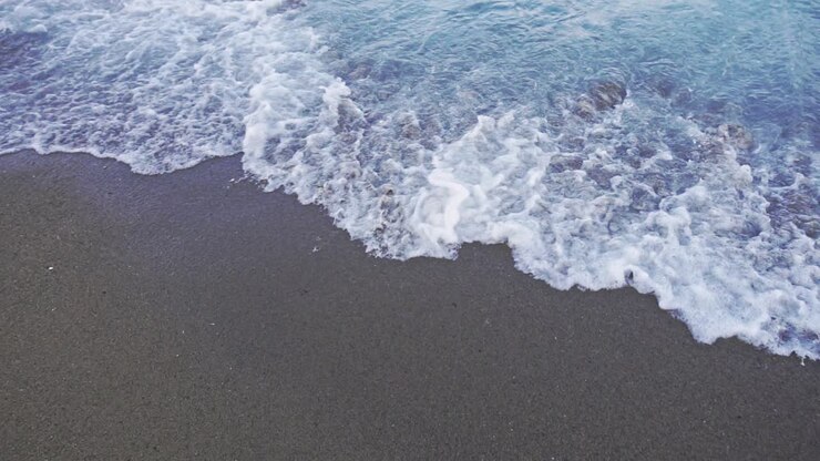 POV di una donna in piedi vicino all'acqua dell'oceano con onde. Donna in spiaggia in vacanza.
