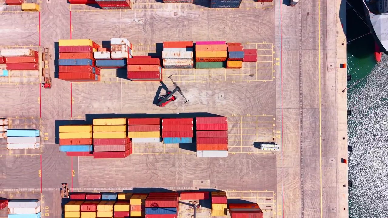 Burgas, Bulgaria, 21 May 2026: Top down view of reach stacker among shipping containers, Burgas, Bulgaria. Direct overhead of colorful containers, yellow bay markings and vessel hull.