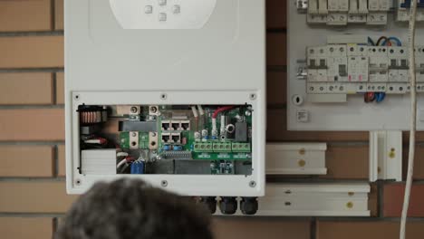 an electrician installing an inverter in a home. the image shows technical skill, modern tools, and attention to safety in electrical work