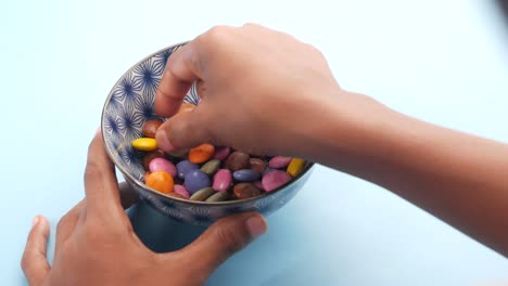 hand picking colorful chocolates from a bowl