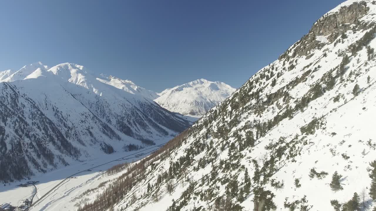 valle alpino con arroyo, carretera y casas individuales entre altas montañas escarpadas