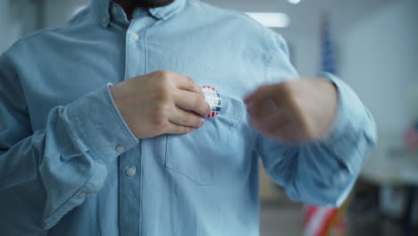 african american us citizen puts on badge with usa flag logo close up of anonymous african american man or us citizen putting on badge with usa flag logo and inscription i voted male voter at polling station after voting election day in the united states