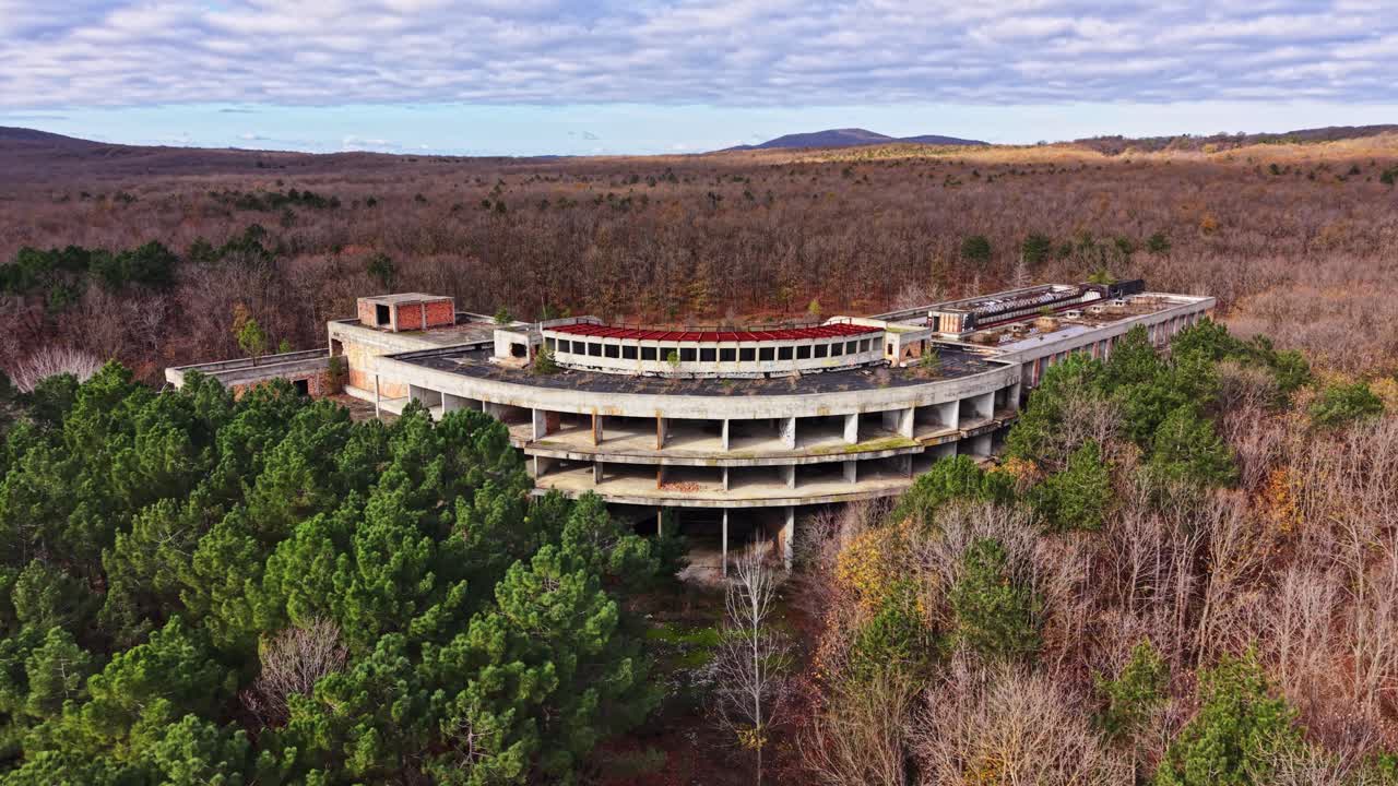 Abandoned structure surrounded by autumn forest in aerial view