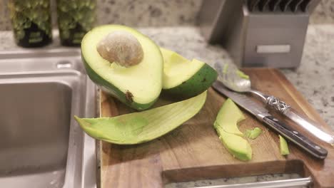 fresh avocado halves with seed on kitchen counter