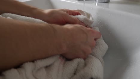 a person washing a hand-print blood stain off of a towel