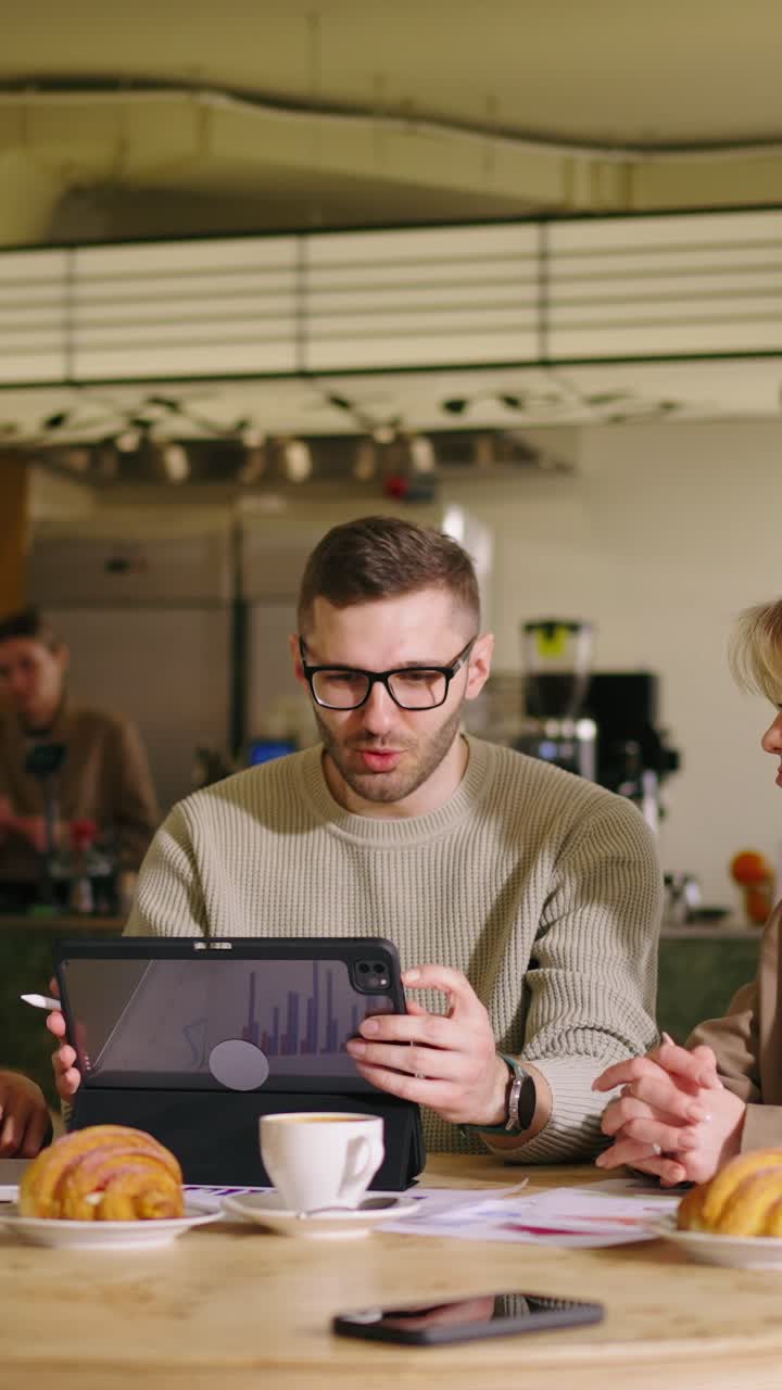 Young Men Collaborating on Tablets in a Modern Cafe