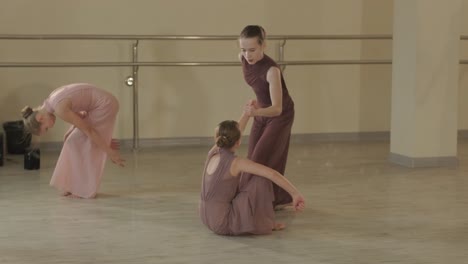 a group of young ballet students in black dancewear practicing positions in a spacious ballet studio with wooden flooring and wall-mounted barres. focused expressions and synchronized movements.