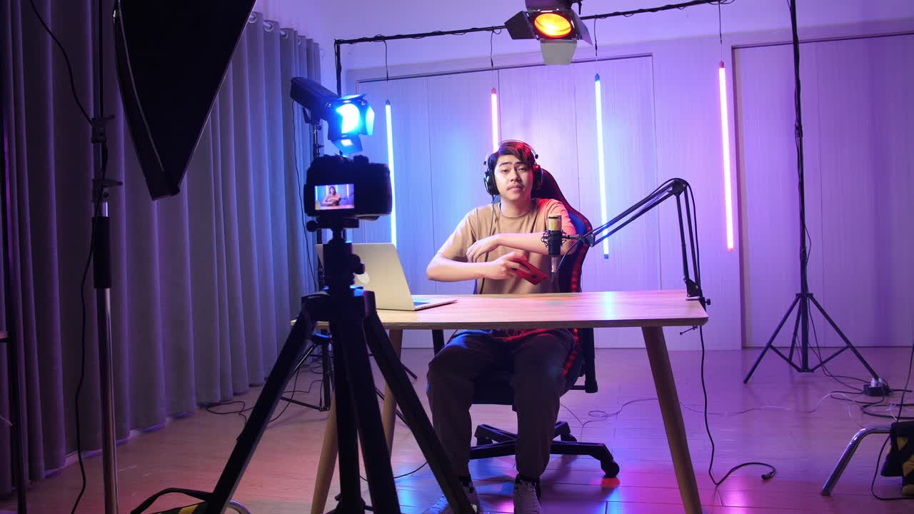 Asian Man Playing Video Game With Mobile Phone Then Pose And Smiles To Camera While Live Stream, Professional Light Equipment