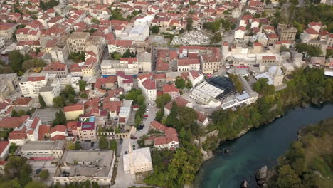 Wide-angle-panoramic-pan-of-Old-town-Mostar-and-Neretva-River,-filmed-from-the-air
