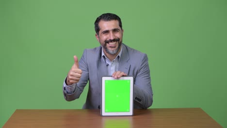 handsome persian bearded businessman showing digital tablet and giving thumbs up