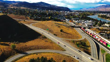 Dolly-En-Drone-Disparó-Hiperlapso-De-Kamloops-Bc-Canadá-Con-Puentes,-La-Autopista-1-Y-La-Autopista-Yellowhead-5-En-Un-Día-Soleado-En-La-Ciudad-Del-Desierto-Con-Automóviles,-Semirremolques-Y-Trenes-Conduciendo-En-Primer-Plano