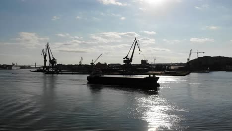 silhouette of oil tanker sailing on smooth water surface approaching port