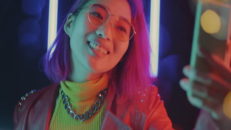 stylish young woman taking a selfie in vibrant neon lighting.