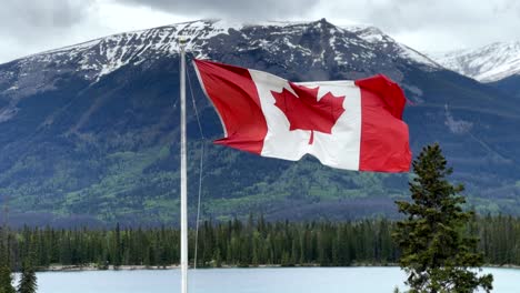 la bandera de canadá ondeando en las montañas rocosas canadienses