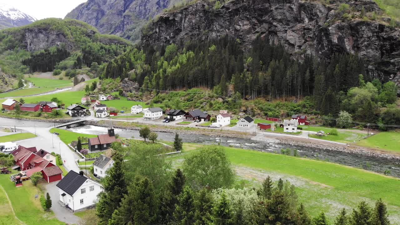 Luftfoto: flyr over Flåmsdalen blant fjell, hus, elver og grønne enger