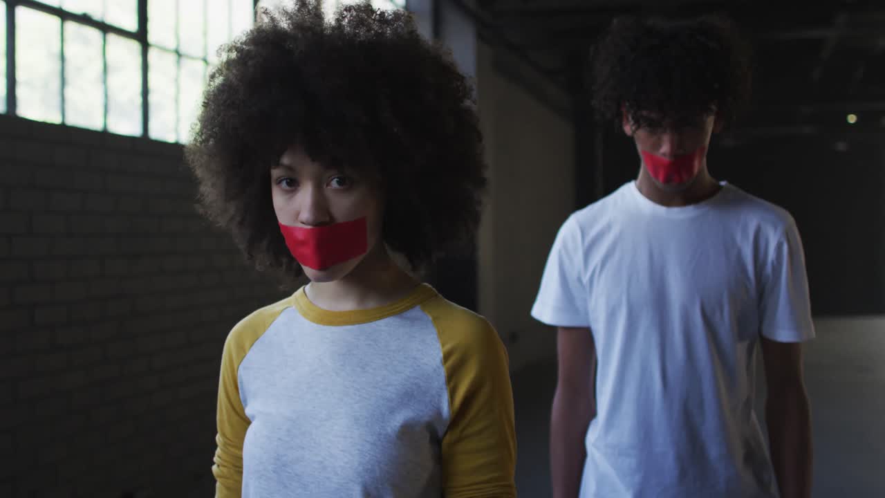 Portrait of african american man and woman with red tape on their mouth in empty parking garage