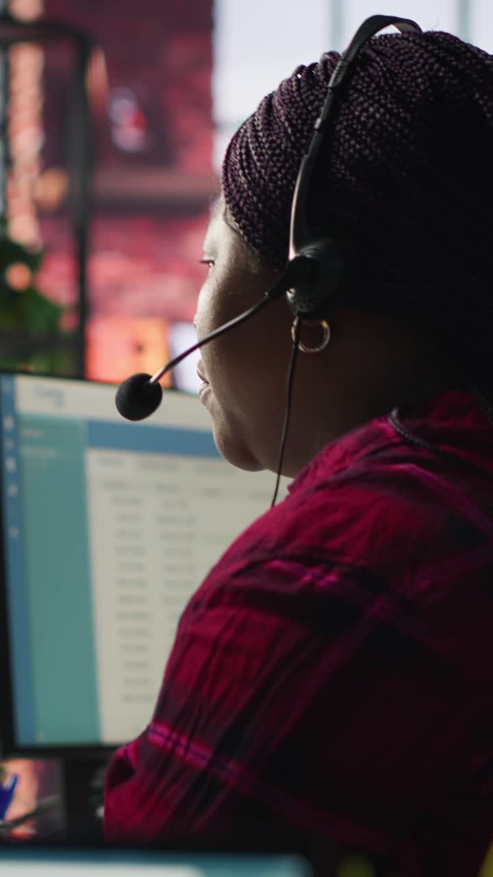 Vertical video IT support specialist at PC in office helping customers during call