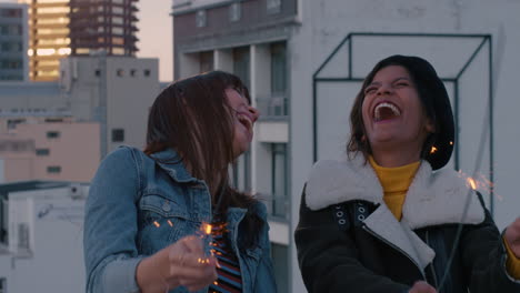 slow motion beautiful young women friends holding sparklers celebrating new years eve on rooftop at sunset dancing having fun enjoying holiday party celebration