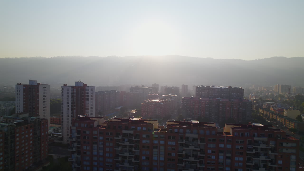 Amanhecer sobre uma área urbana com edifícios residenciais altos e árvores verdes.