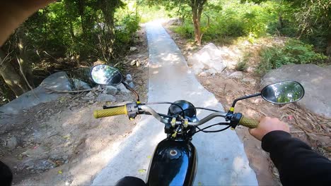 pov-opname van een motorrijder die op een smal rotsachtig pad rijdt, omringd door het idyllische natuurlandschap van vietnam