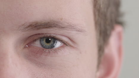 young man eye opening beautiful blue iris looking at camera macro close up