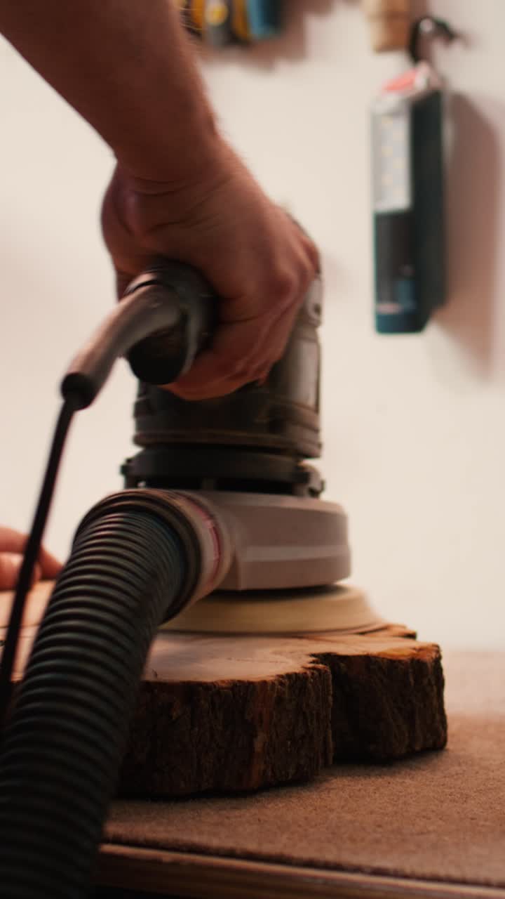 Close-up of a Hand Sanding Wood with an Orbital Sander in a Workshop