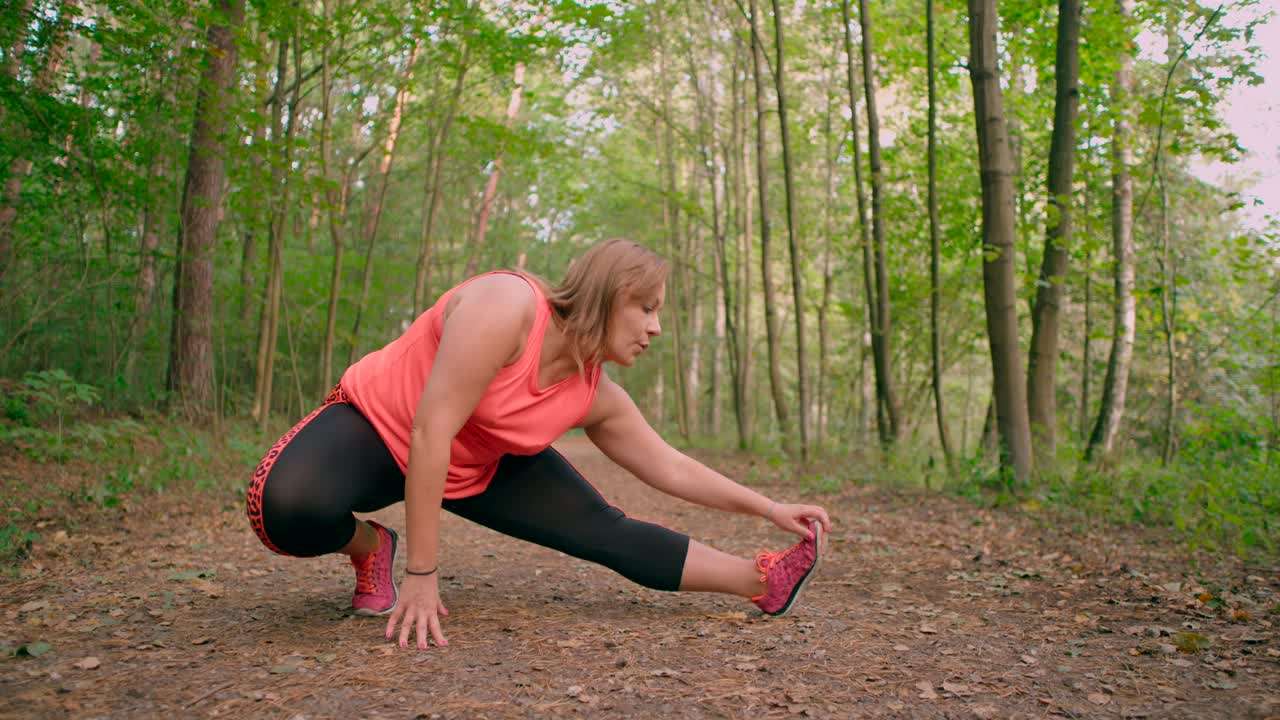mujeres caucásicas en ropa deportiva estirando las piernas y haciendo ejercicio en el sendero del bosque