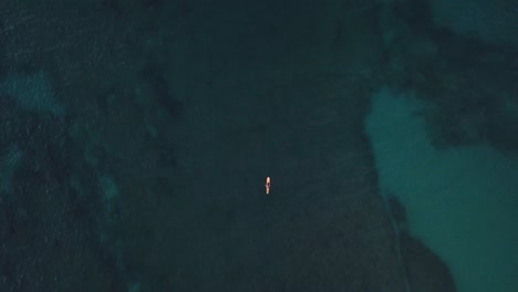 Drone-Shot-rising-above-a-lone-surfer-sitting-on-his-board-waiting-for-a-wave