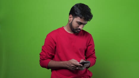 Joven-Loco-Sosteniendo-Su-Teléfono-Inteligente-Celular-Contra-El-Fondo-Verde-De-La-Llave-De-Croma