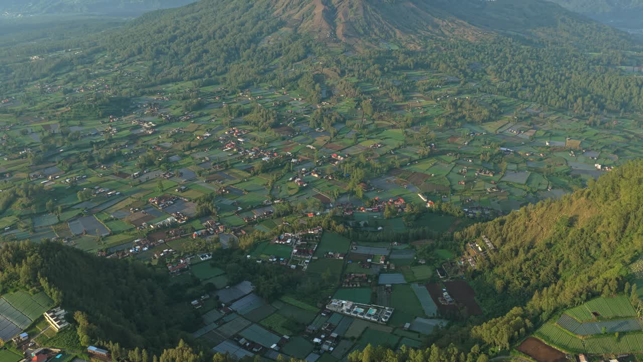 Vista aérea sobrevoando campos de arroz em direção ao vulcão Batur em Bali.