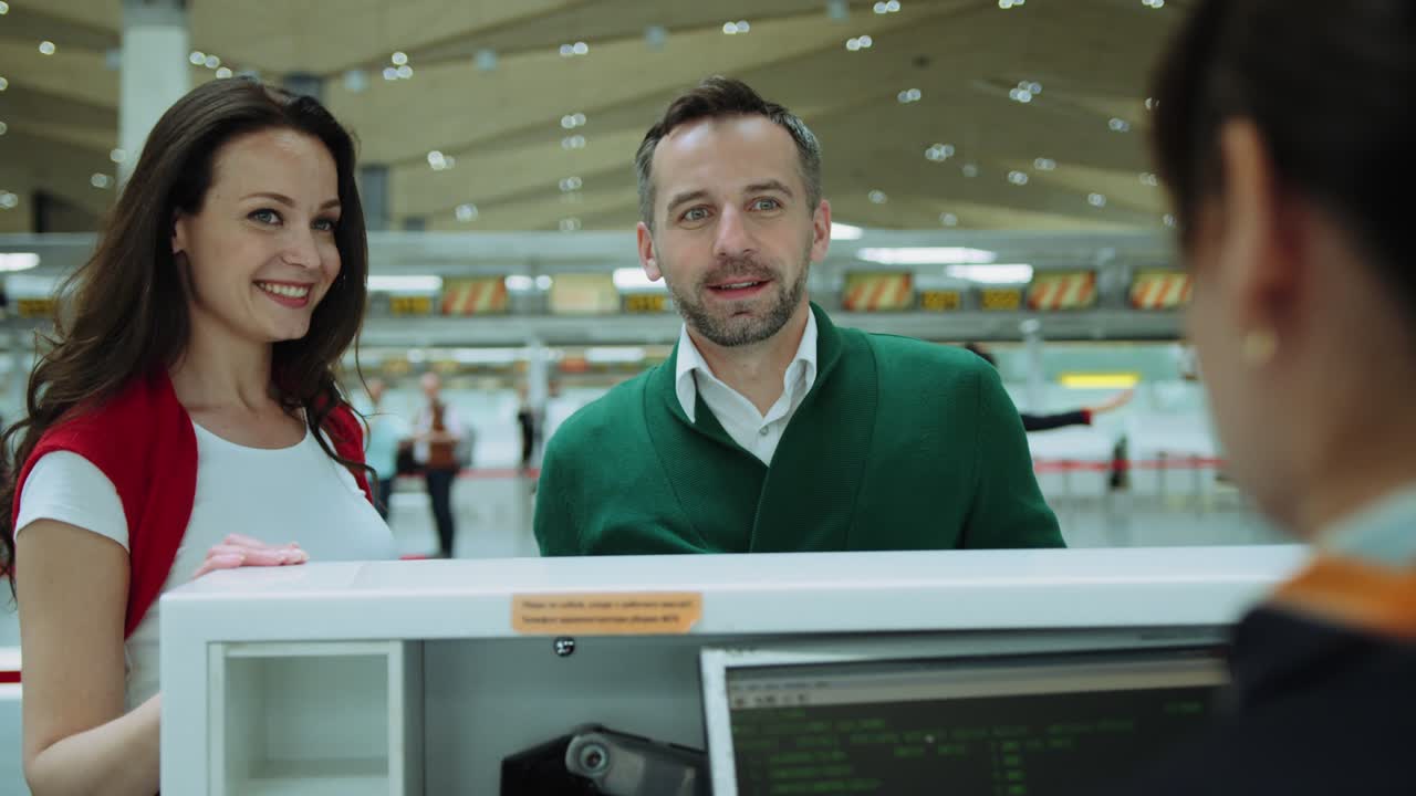 Happy couple At Airport with two red suitcases Check In Desk Leaving On Vacation. Cinematic shot on RED camera.