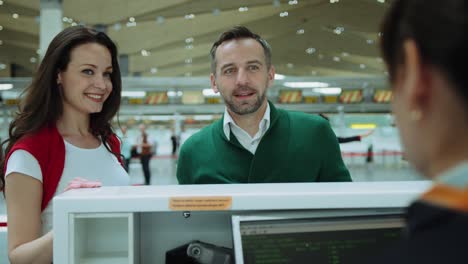 happy couple at airport with two red suitcases check in desk leaving on vacation. cinematic shot on red camera.