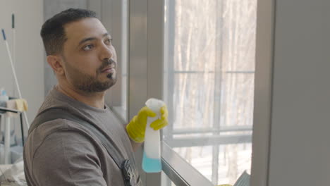 Nahaufnahme-Eines-Arabischen-Putzmanns,-Der-Die-Fensterscheiben-Mit-Einem-Lappen-Und-Einem-Glasreiniger-In-Einem-Büro-Reinigt-1