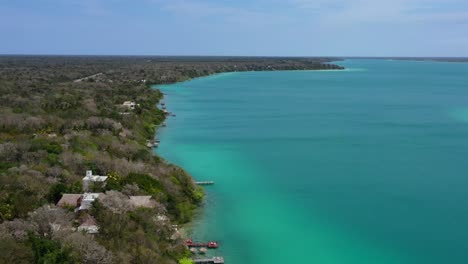 wide aerial coastline of turquoise blue bacalar lagoon coastline on sunny day in mexico