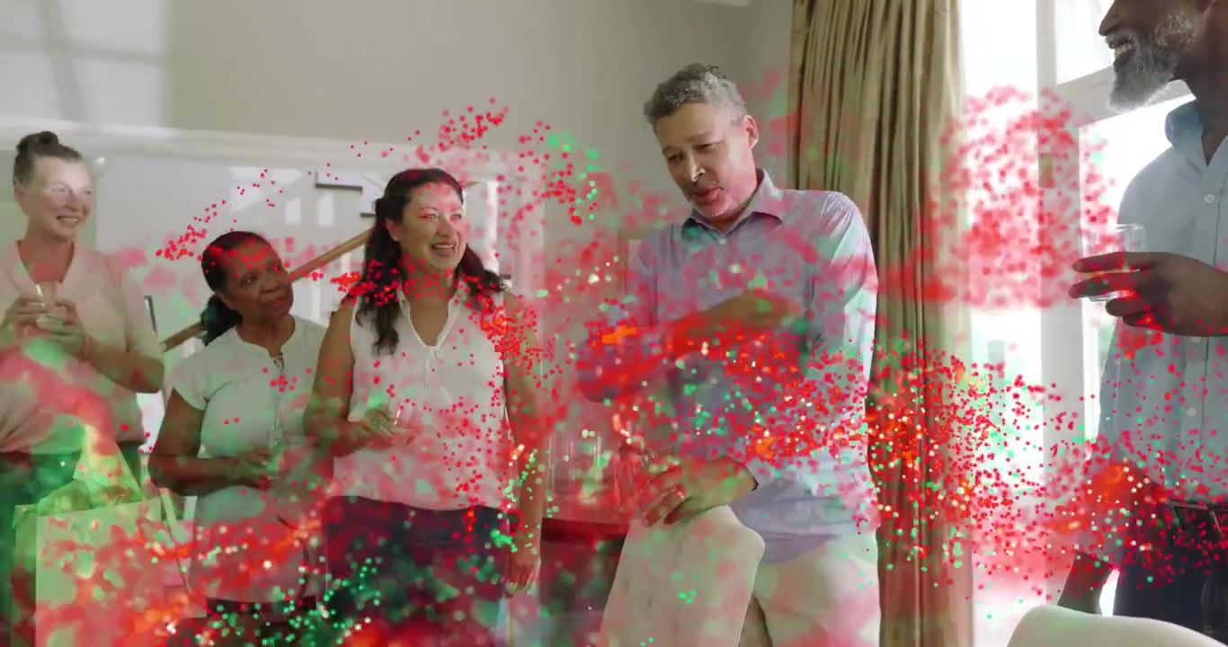 Host speaking gesturing to right man sparking red-green confetti drifting over group for event