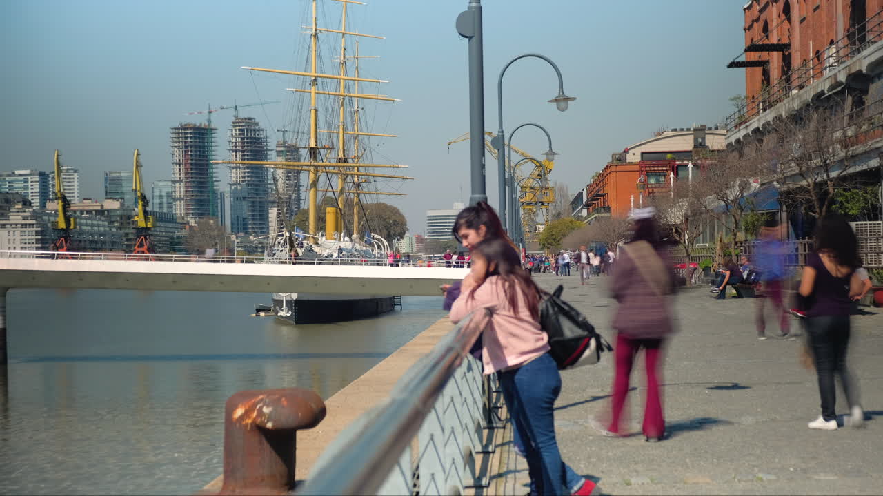 People walking and staring in Madero Port with Sarmiento Frigate and Woman’s Bridge in background at daytime time lapse