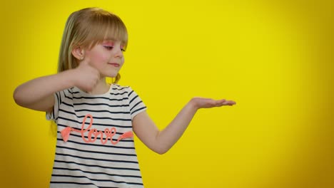 cute little girl pointing and presenting on yellow background