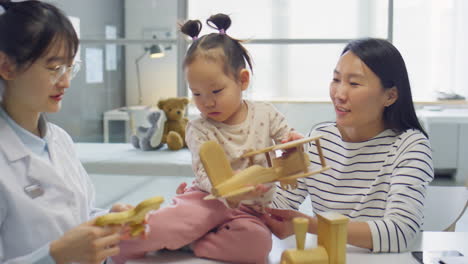 asian toddler girl playing with toys in medical office